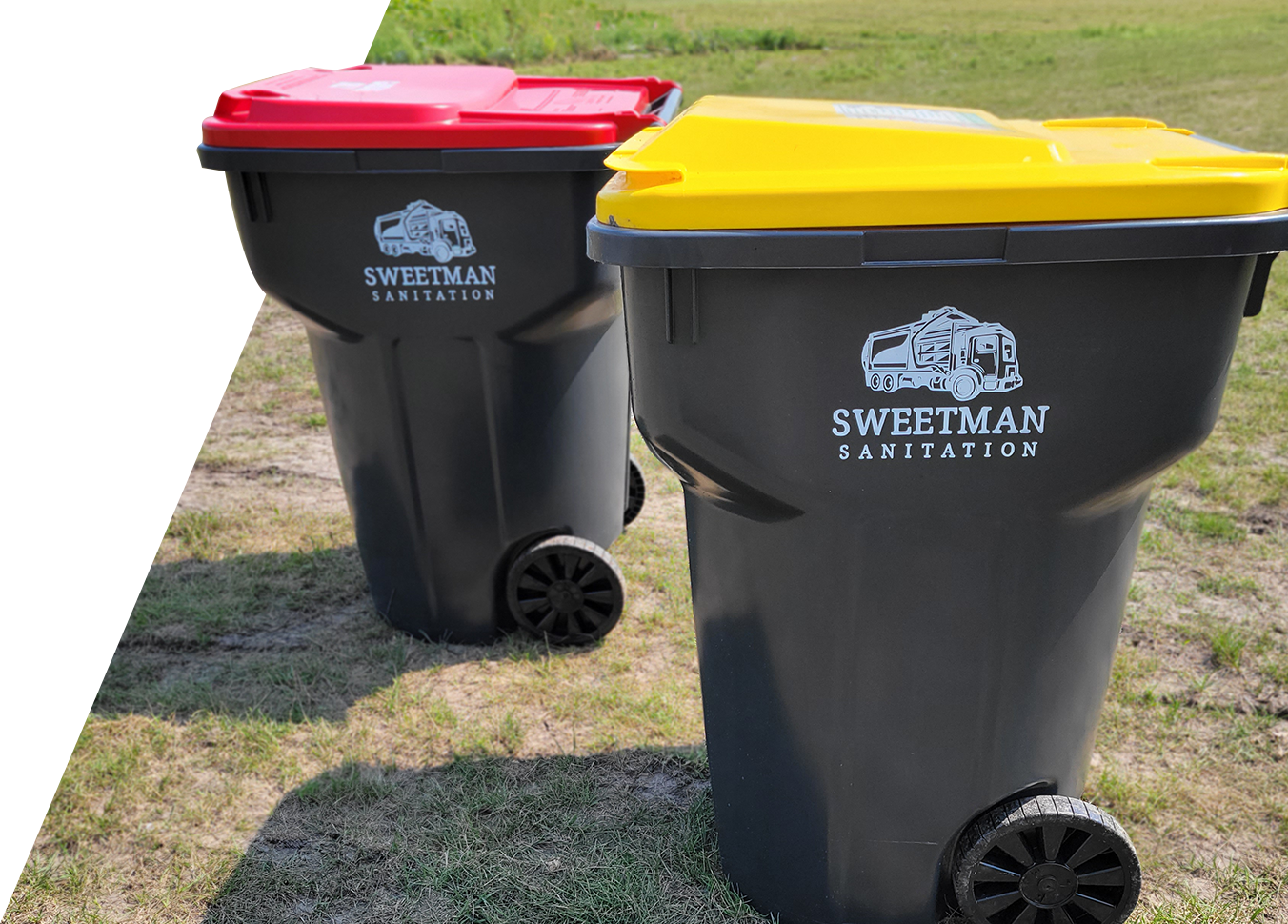 Two trash cans on wheels in a field.