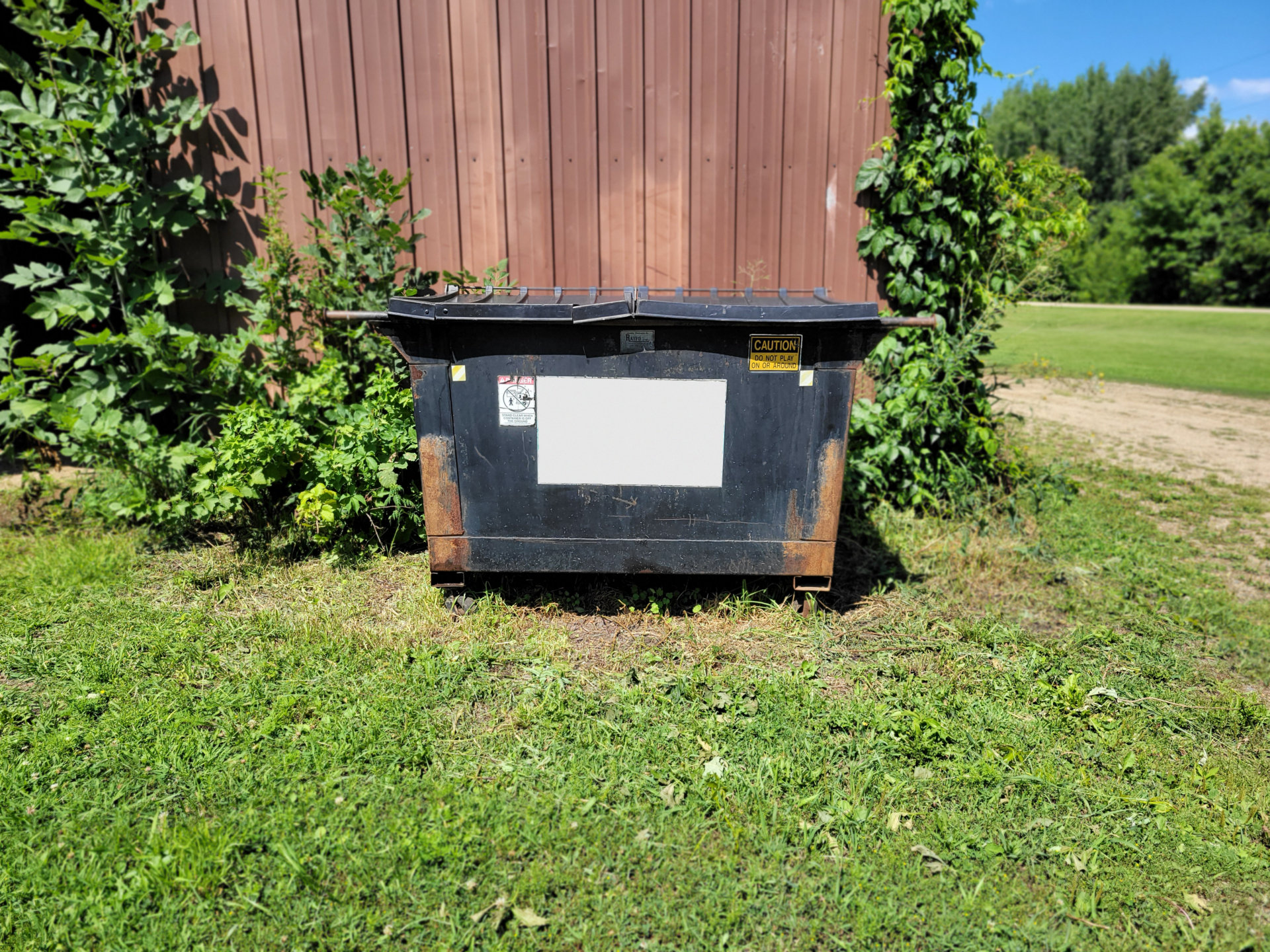 Rusty Black Dumpster on Rural Site